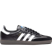 Black leather Adidas skateboarding shoe with white leather stripes and brown rubber sole. Suede toe cap.