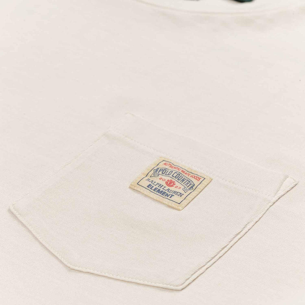 Polo Ralph Lauren x Element Pocket Tee in cream. Small front pocket on left breast with small square sewn on patch. Close up photo of Polo Ralph Lauren x Element logo on patch in red and blue.